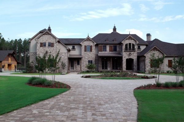 A large brick house with a lot of green grass.