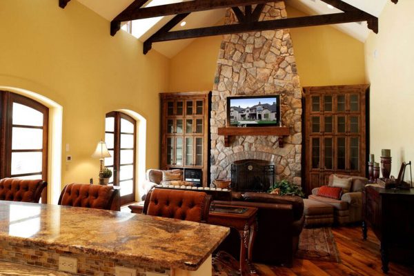 A living room with a stone fireplace and wooden floors