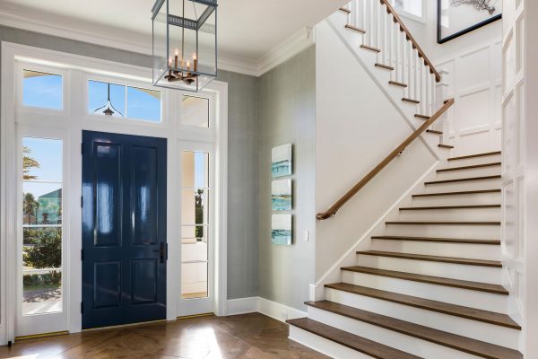 A foyer with a blue door and white stairs.