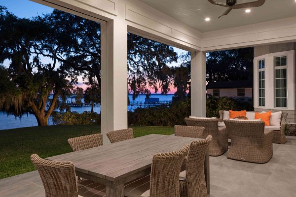 A patio with a table and chairs, overlooking the water.