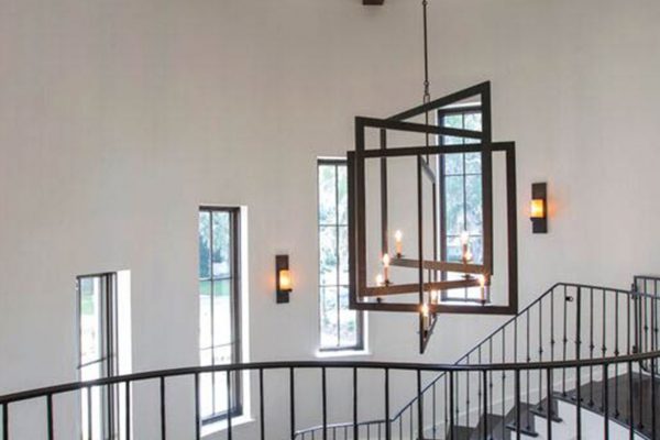 A staircase with a metal railing and a chandelier.